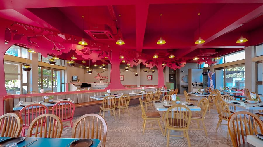 An image of a restaurant featuring chairs, tables, colourful tree cutouts on top with ceiling lights at Pride Resort Ambaji